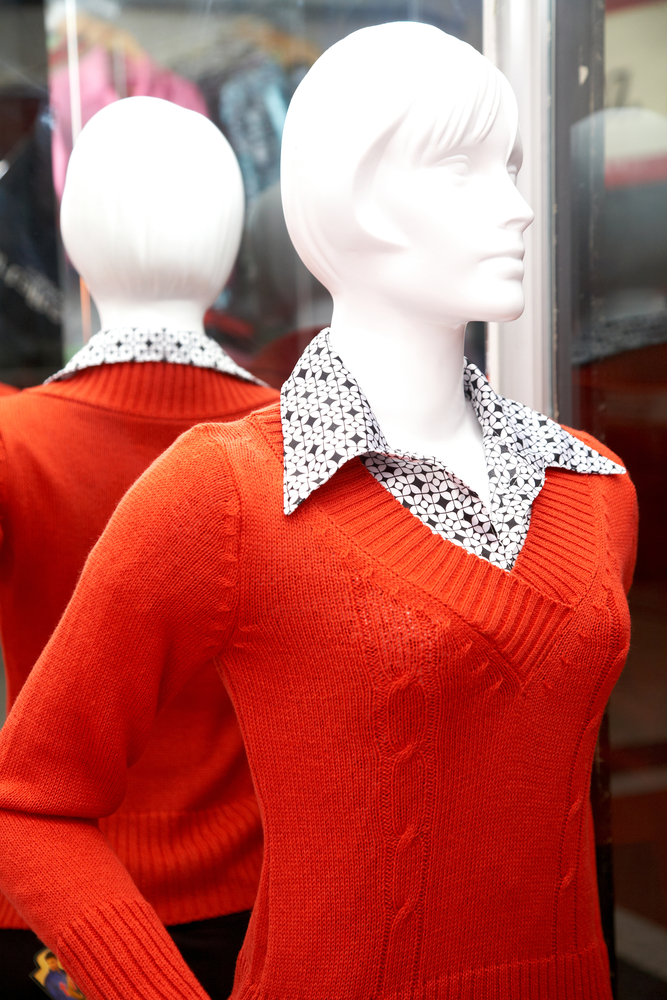 mannequin in a clothes store wearing an orange jumper